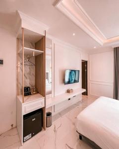 een slaapkamer met een bed en een tv aan de muur bij Kala Hotel Semarang in Jomblang