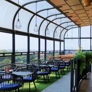 a restaurant with tables and chairs and windows at Kala Hotel Semarang in Jomblang