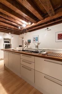 a large kitchen with white cabinets and a wooden ceiling at Bellissimo appartamento in Palazzo Storico in Venice