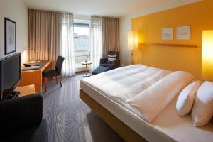 a hotel room with a large bed and a desk at Parkhotel Pforzheim in Pforzheim