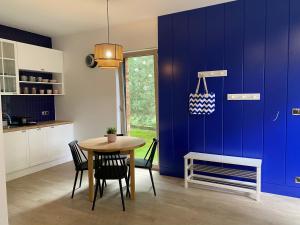 a kitchen with a table and a blue wall at Apartament Poezja Ciszy in Dębki