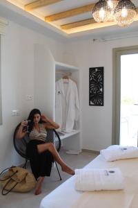 Una donna seduta su una sedia in una camera da letto di LEMONIA STUDIOS&SUITES ad Agia Anna Naxos