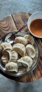 a plate of dumplings on a table with a bowl of soup at The cottage and cheese in Manāli