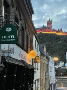 a hotel sign on a building with a castle in the background at Hotel und Gästehaus Gute Quelle in Cochem