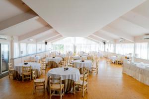 uma sala cheia de mesas e cadeiras com toalhas de mesa brancas em Le Dune Sicily Hotel em Catânia