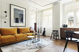 a living room with a yellow couch and tables at Witkacownia Apartament in Toruń