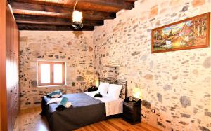 a bedroom with a bed in a stone wall at Afroditi Traditional Villa in Yiannioú