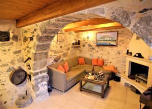Una sala de estar con un sofá y una pared de piedra. en Afroditi Traditional Villa, en Yiannioú