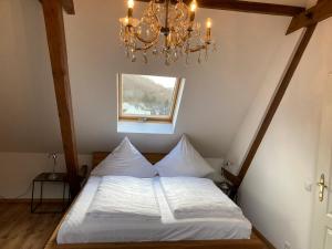 a bedroom with a white bed with a chandelier at FEWO Königsberg Weingut C A Haussmann in Traben-Trarbach