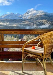 a wicker chair on a deck with a view of mountains at Apart 64 Guest House in Krasnaya Polyana