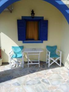 un patio con 2 sillas, una mesa blanca y armarios azules en DARZENTA ATHINA BEACH HOUSES, en Perivolos