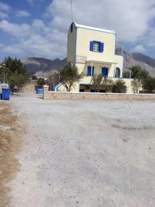 a white building with blue windows on a dirt road at DARZENTA ATHINA BEACH HOUSES in Perivolos