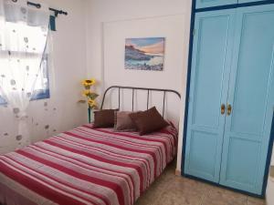 プエルト・デ・サンティアゴにあるOcean Viewの青いドアの横に縞模様の毛布が敷かれたベッド