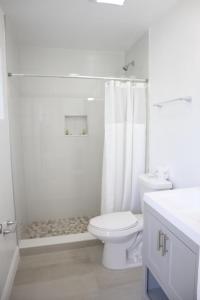 a white bathroom with a toilet and a shower at Singer Island Inn/ Deluxe Studio in West Palm Beach
