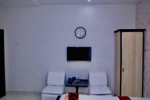Hotel Tulip Inn في لاهور: غرفة بها كرسيين وساعة على الحائط