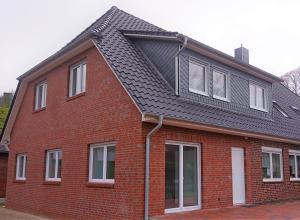 a red brick house with a black roof at Ferienwohnungen Im Dorfe Neu ab April 2022 in Soltau