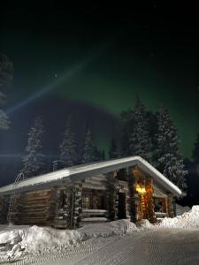 une cabane en rondins dans la neige la nuit dans l'établissement Kuusiruka, à Ruka