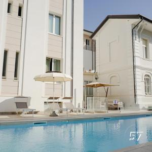 uma piscina com cadeiras e guarda-sóis ao lado de um edifício em Hotel Regina Elena 57 & Oro Bianco SPA em Rimini