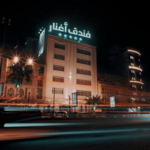 a building with a sign on top of it at night at Aghnar Hotel in An Najaf