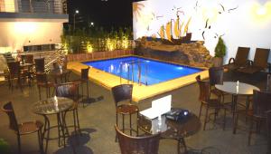 um restaurante com piscina, mesas e cadeiras em Hotel Colombo em Barra do Garças