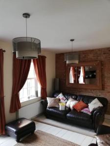 a living room with a leather couch and a window at Stay in our beautiful 1850’s Coastguards Cottage. in Felpham