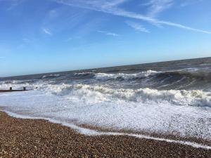 a beach with the ocean and waves at Stay in our beautiful 1850’s Coastguards Cottage. in Felpham