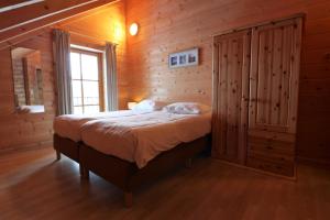 a bedroom with a bed and a wooden wall at Vakantiehuis Luxe BlokhuisA in Willingen