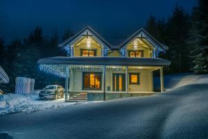 une maison avec une voiture garée dans la neige dans l'établissement WhiteWood Cottages, à Bukovel