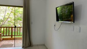 einen Flachbild-TV, der an einer Wand neben einem Fenster hängt in der Unterkunft Loft Reserva Sapiranga Praia do Forte Vila Hen 102 in Mata de Sao Joao