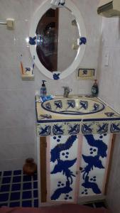 uma casa de banho com um lavatório azul e branco e um espelho. em Casa Santita Por Habitación em Santa María del Tule