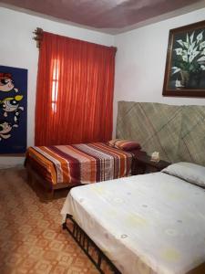 a bedroom with two beds and a red curtain at Casa Santita Por Habitación in Santa María del Tule