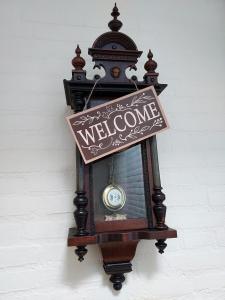 une horloge suspendue sur un mur avec un panneau de bienvenue dans l'établissement B&B de Sluis, à Rosmalen