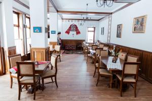 a restaurant with tables and chairs and a man standing in the background at Casa Marta in Sâmbăta de Sus