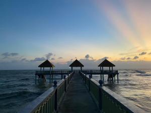 a pier stretches out into the ocean at sunset at Desaru Happy Guest House D in Desaru