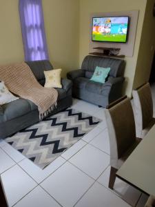 a living room with two couches and a flat screen tv at Chalé para temporada no Centro de Guaramiranga in Guaramiranga