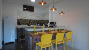 eine Küche mit einer Holzbar mit gelben Stühlen in der Unterkunft Casa no Caravaggio ao lado da cervejaria 3 Santas in Santa Teresa
