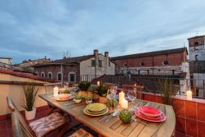 un tavolo in legno con piatti e candele su un balcone di Terrazza Santa Croce, PANORAMIC TERRACE PENTHOUSE inside the Walls of Lucca a Lucca