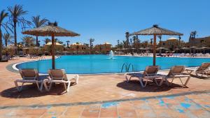 una piscina en un complejo con sillas y sombrillas en Papagayo 21-22, big pool and free WIFI, en Corralejo