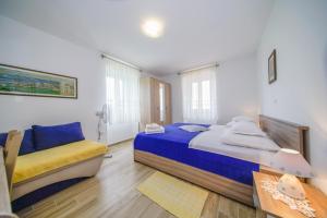 een slaapkamer met een bed, een stoel en een tafel bij Apartment Akacija in Postira