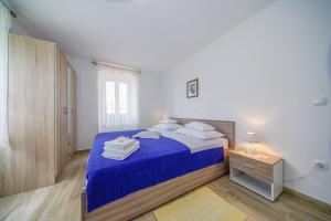 een slaapkamer met een bed met blauwe lakens en witte kussens bij Apartment Akacija in Postira
