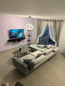 uma sala de estar com um sofá e uma televisão de ecrã plano em Royal Resort em Eilat