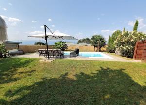 um pátio com um guarda-sol e cadeiras e uma piscina em B&B L'orto del Geo em Cavour