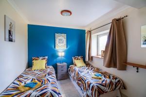 2 camas en una habitación con paredes azules en Gîte Sarlat en Savignac-sur-Leyze