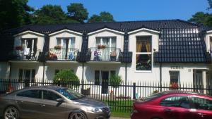two cars parked in front of a white house at Pensjonat Perła in Pobierowo