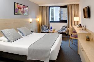 a hotel room with a bed and a desk at Hôtel Padoue in Lourdes