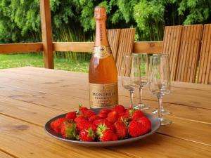 una botella de champán y un plato de fresas en una mesa en Moulin de l'Hoste en Larzac