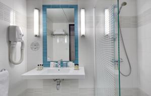 a white bathroom with a sink and a shower at Hôtel Padoue in Lourdes