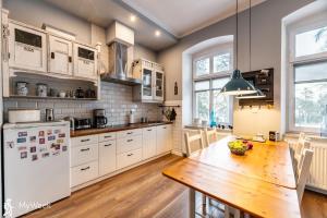 a kitchen with a wooden table and a white refrigerator at Apartament w centrum Karpacza, MyWeek in Karpacz