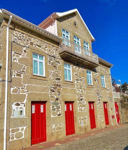 a stone building with red doors and a balcony at Casa de São Marcos in Manteigas