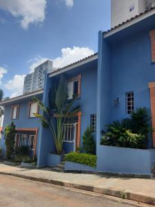 uma casa azul com uma palmeira em frente em Charmosa casa em condominio com quintal em São Paulo